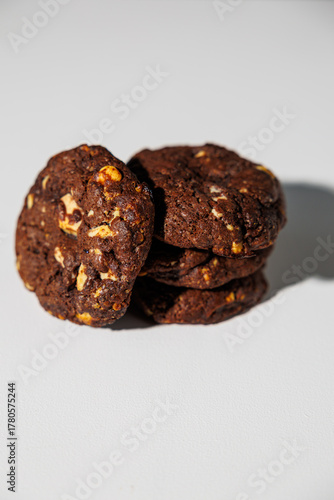 A stack of rich double chocolate cookies with nut chunks arranged on a white surface, showcasing texture and contrast. No visible branding