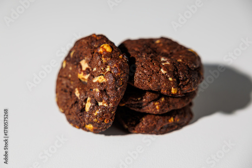 A stack of rich double chocolate cookies with nut chunks arranged on a white surface, showcasing texture and contrast. No visible branding