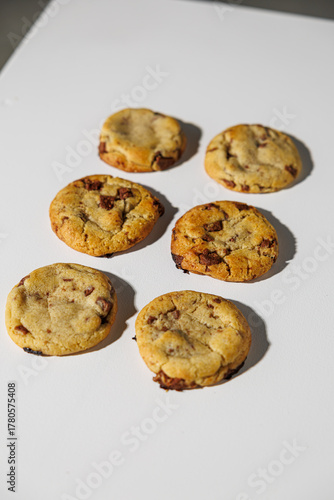 A set of six golden-brown chocolate chip cookies arranged in two neat columns on a clean white surface. No visible logos or branding