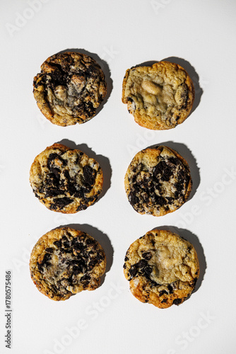 A set of six freshly baked cookies topped with crushed chocolate sandwich cookies, arranged neatly on a white background. No logos or branding present