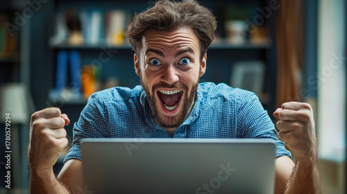 Joyful man celebrating a victory while working on his laptop in a cozy indoor space during the daytime