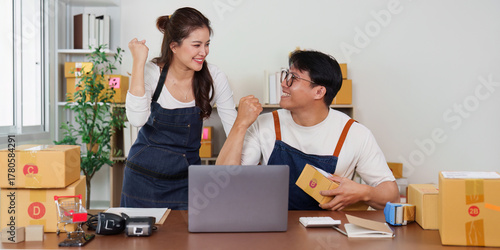 E-commerce Success. Young entrepreneurs celebrating achievement in a startup office.