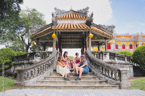 Group of women travelers sitting on ancient temple steps, exploring vietnamese heritage, and experiencing a cultural vacation in the historic city of hue