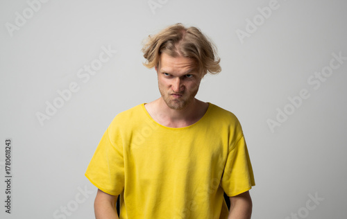 Papier peint Annoyed man in yellow shirt frowning and showing displeasure during studio portr