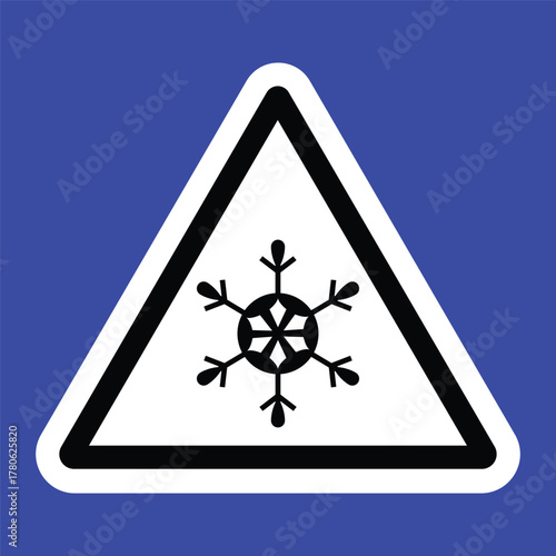 Triangular warning sign with a black snowflake symbol on a white background and blue border, indicating icy or cold surface caution. Ideal for safety signage and winter hazard alerts.