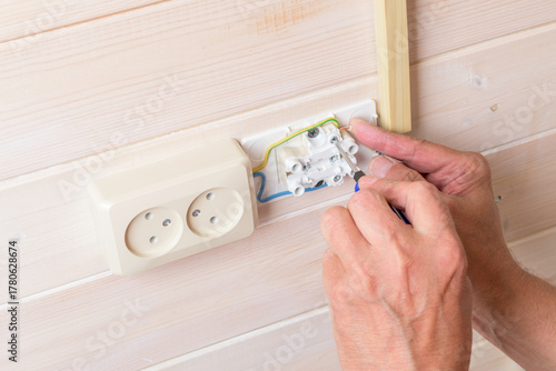 Bilde på lerret Close view of person fastening double socket on light wood paneling with screwdriver; hands steady, tidy tools, calm repair mood