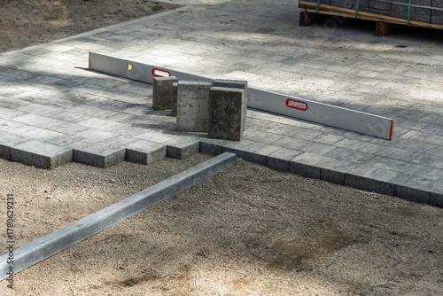 Outdoor paving work with stacked concrete blocks and a spirit level on a sunny day, tactile texture and progress detail.