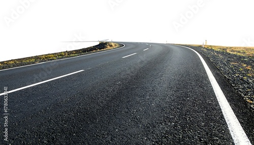 A curving asphalt road disappears toward a bright white horizon. It has white painted lines with sparse vegetation at road sides