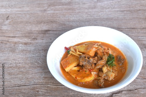 spicy boiled slice fresh bamboo shoot with beef meat topping in coconut milk curry soup on bowl