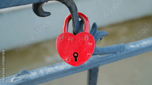 Red heart-shaped love lock on metal railing symbolizing affection and romance