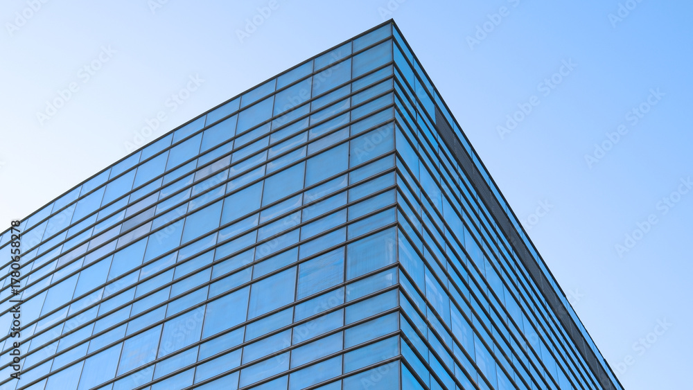 Fototapeta premium Glass facade of contemporary building reflecting clear blue sky
