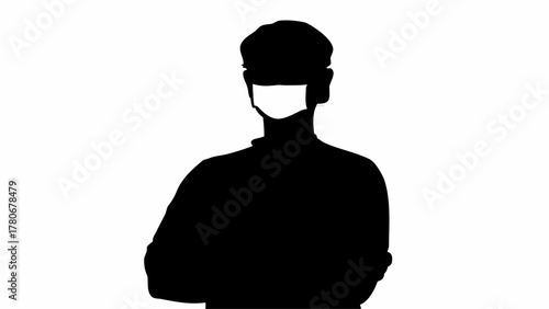 Silhouette of a person wearing a mask and a hat with arms crossed in a black and white image