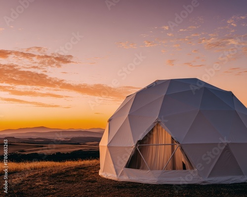 Modern Geodesic Dome at Sunrise Over Hilly Landscape