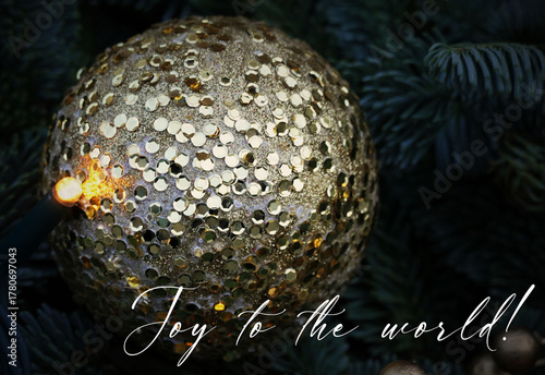 Joy to the world - big golden sparkling ball Christmas decoration on dark background with Christmas greetings