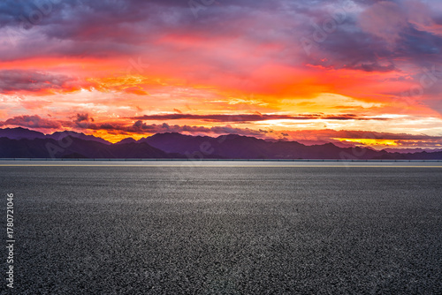 Empty asphalt road and beautiful mountain range with dramatic sky clouds at sunset