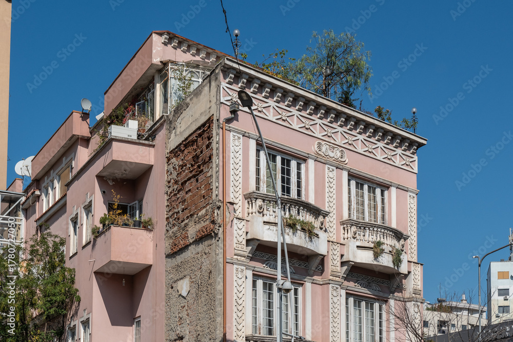 Obraz premium Verzierte Fassade eines rosa Altbaus mit Balkon im Sonnenlicht, Tirana, Albanien