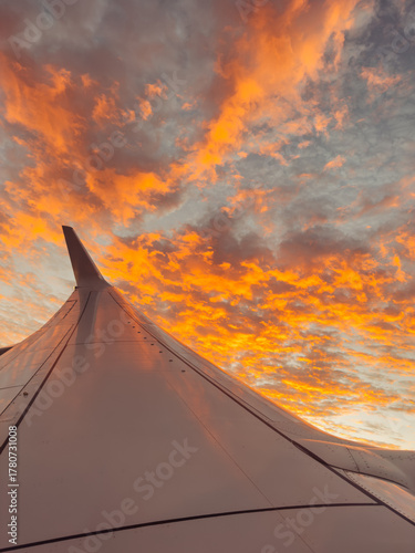 Canvas Print Sunrise clouds in sky over airplane wing during travel
