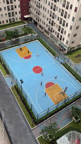 aerial bird eye view of a basketball court. basketball game on the sport field in an apartment residence. sport and leisure activity in park. outdoor basketball field court. people playing basketball