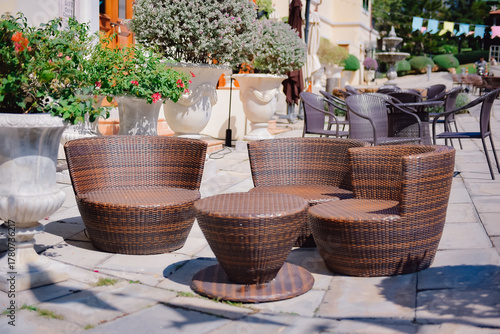 Outdoor synthetic rattan chairs and coffee table set up in front of a cafe, creating a relaxing spot for tourists to unwind.