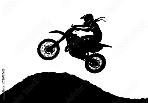 Motorcyclist in mid-air jump over dirt hill with flowing hair and helmet