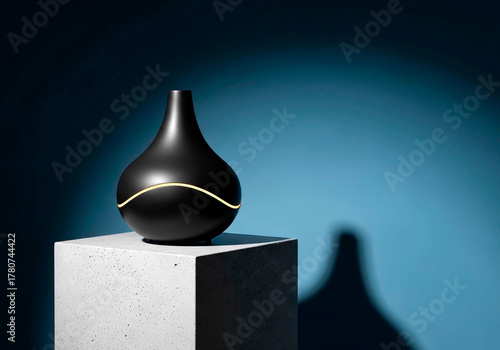 A modern black aroma diffuser with a glowing light accent on a concrete pedestal. Minimalist product photography against a dark blue background with copy space