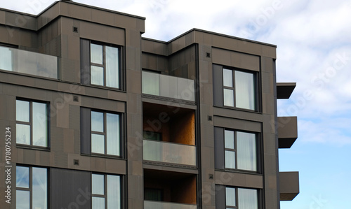 Exterior of modern dark cladding house object. Architectural detail of recessed balconies and windows. Real estate, urban living, and property marketing.
