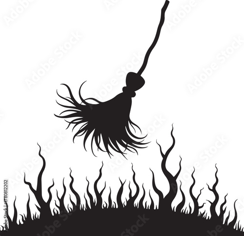 Black silhouette of a witch's broom over fiery grass