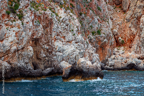 Fototapeta Naklejka Na Ścianę i Meble -  Suluada Island Mediterranean Shoreline Featuring Light-Colored Cliffs with Reddish Veins, Antalya, Turkey