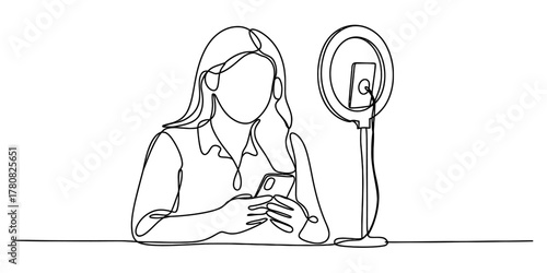 Continuous line drawing of a woman using a smartphone next to a ring light setup, symbolizing social media engagement and modern online content creation.