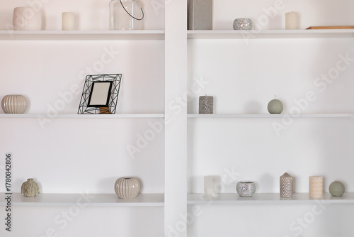 Wooden shelves with decor, candles, frame and vases in interior design room. Minimalist at home. Cozy light home style. Scandinavian interior.