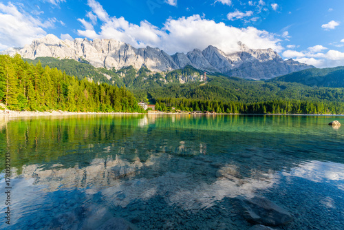Eibsee Lake, Mountain Slopes with Forest and Zugspitze Massif on Sunny Day. Ripple on Water. Bavaria, Germany