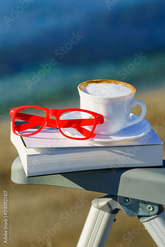 Coffee cup and book on sea coast