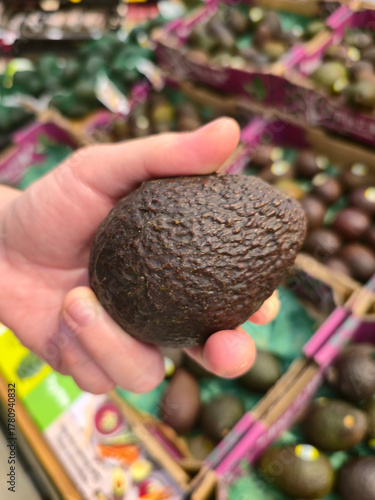 Hand Holding Ripe Avocado at Grocery Store