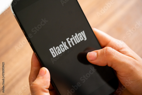 Black Friday photo. Minimalist Black Friday symbol with cell phone in hands and discount offer. Horizontal design for Black Friday sales, advertising, and social media.