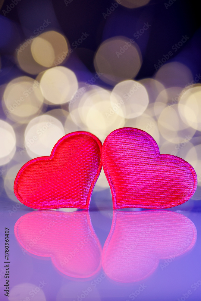 Fototapeta premium Two red hearts with golden bokeh lights. Romantic holiday background for Valentine’s Day, anniversary, wedding, or New Year greeting cards. Symbol of love, joy, and celebration.