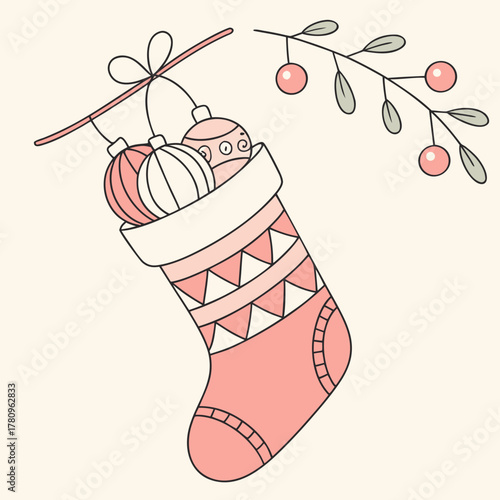 Pink christmas stocking filled with ornaments hanging with a branch of berries decoratively