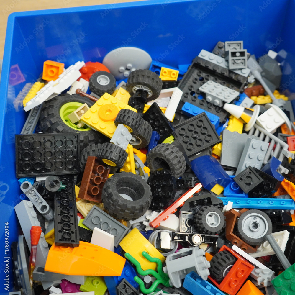 Fototapeta premium Colorful assortment of toy building blocks in a blue storage container