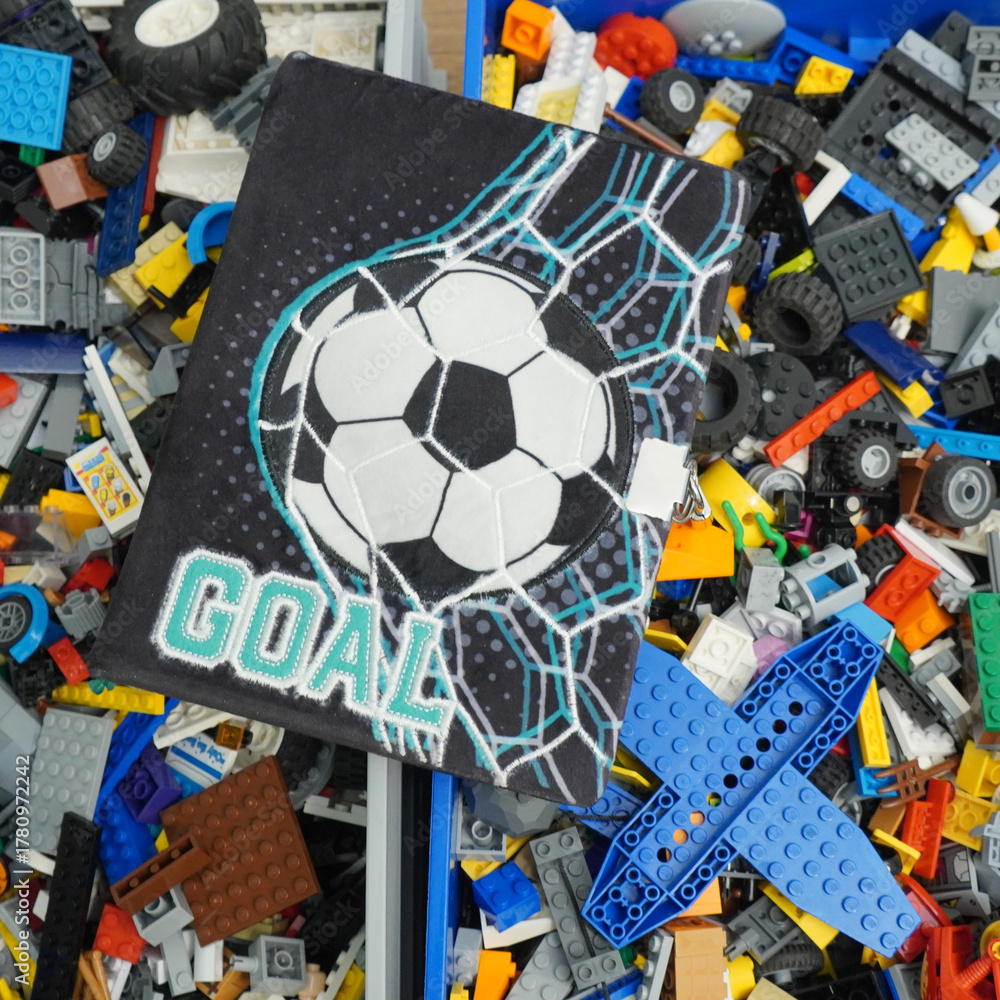 Fototapeta premium Soccer-themed notebook with a goal design surrounded by colorful toy blocks
