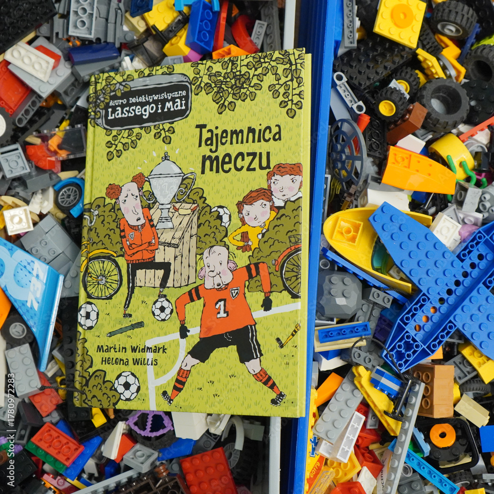 Fototapeta premium Book cover of Tajemnica Meczu by Martin Widmark and Helena Willis in a pile of toys