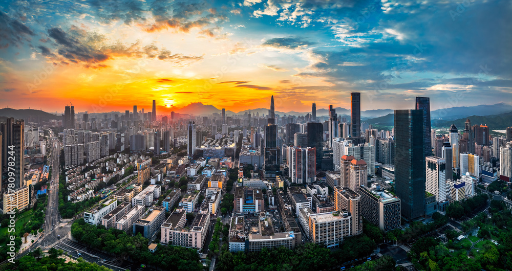 Fototapeta premium Panoramic of the dense urban city skyline with modern skyscrapers under a golden sunset sky in Shenzhen, China.