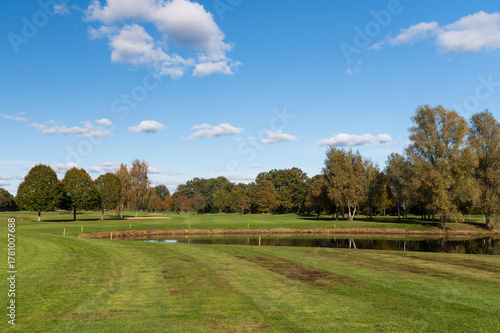 Golf course with pond and trees under clear blue sky
