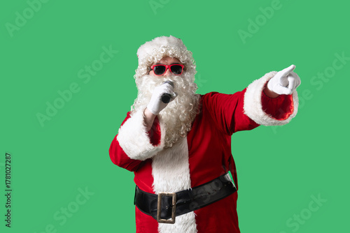 Wallpaper Mural Santa Claus, with a white curly beard, wearing a red suit and sunglasses, sings songs into a microphone and dances cheerfully against a green background. Ideal for Christmas themed compositions. Torontodigital.ca