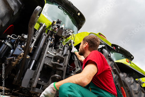 Agricultural technician repairing farm machinery outdoors