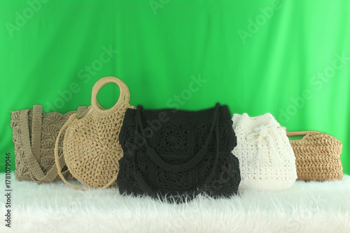 Crocheted bags in different colors and varieties arranged on a white fluffy blanket in front of a green background.