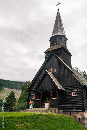 Gjøra Chapel sits in Gjøra village, offering a view of its striking wooden historic building against a backdrop of green mountains and overcast skies, Møre og Romsdal county, Norway