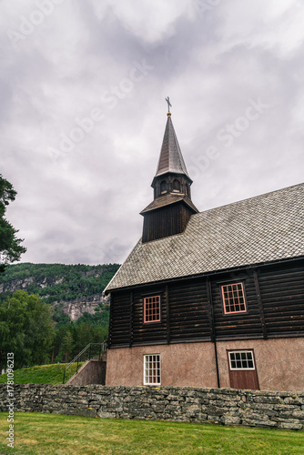 Gjøra Chapel sits in Gjøra village, offering a view of its striking wooden historic building against a backdrop of green mountains and overcast skies, Møre og Romsdal county, Norway