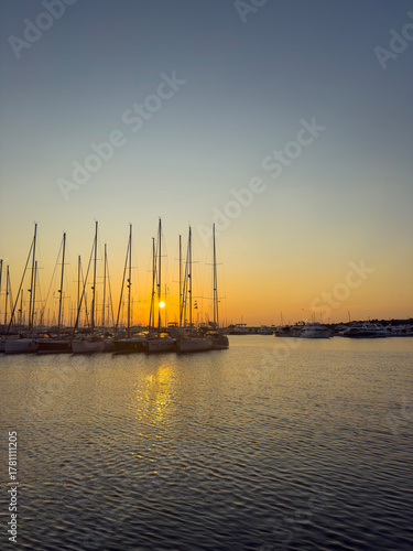 Golden Sunset over a Marina with Silhouetted Sailboats