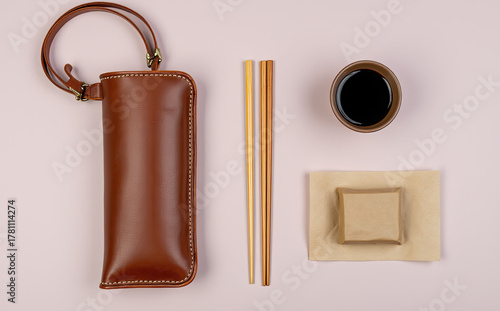 Brown leather case with golden chopsticks and soy sauce image