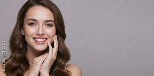 Happy young woman with a healthy white smile. Beauty portrait with clear skin and wavy brown hair. Skincare, cosmetology and dental care concept