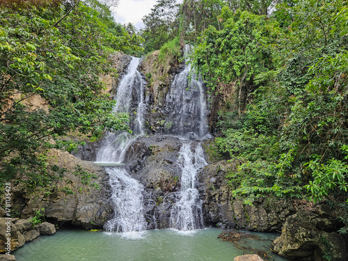 A picturesque multi-tiered waterfall, The Nest, in Nayarit, Mexico. Surrounded by vibrant green tropical jungle, its clear waters cascade over dark rocks into a tranquil pool below